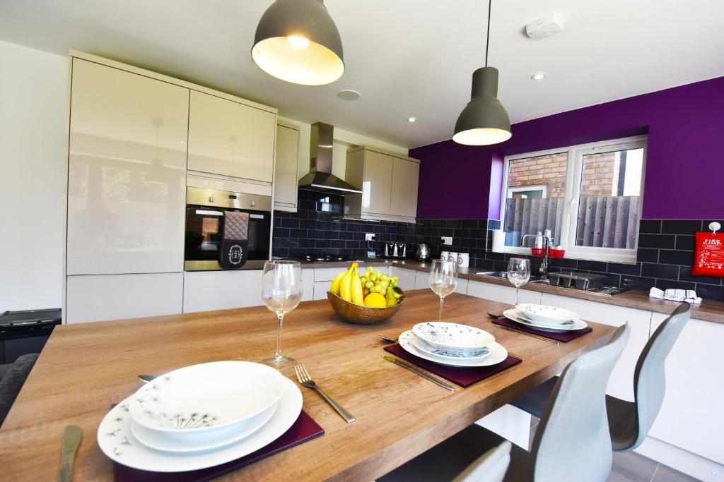 a kitchen with a wooden table with plates and wine glasses at Gorse House in Leicester