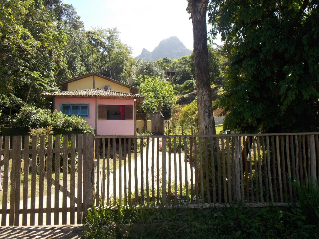 a house behind a wooden fence with a tree at Casa em Ilhabela in Ilhabela