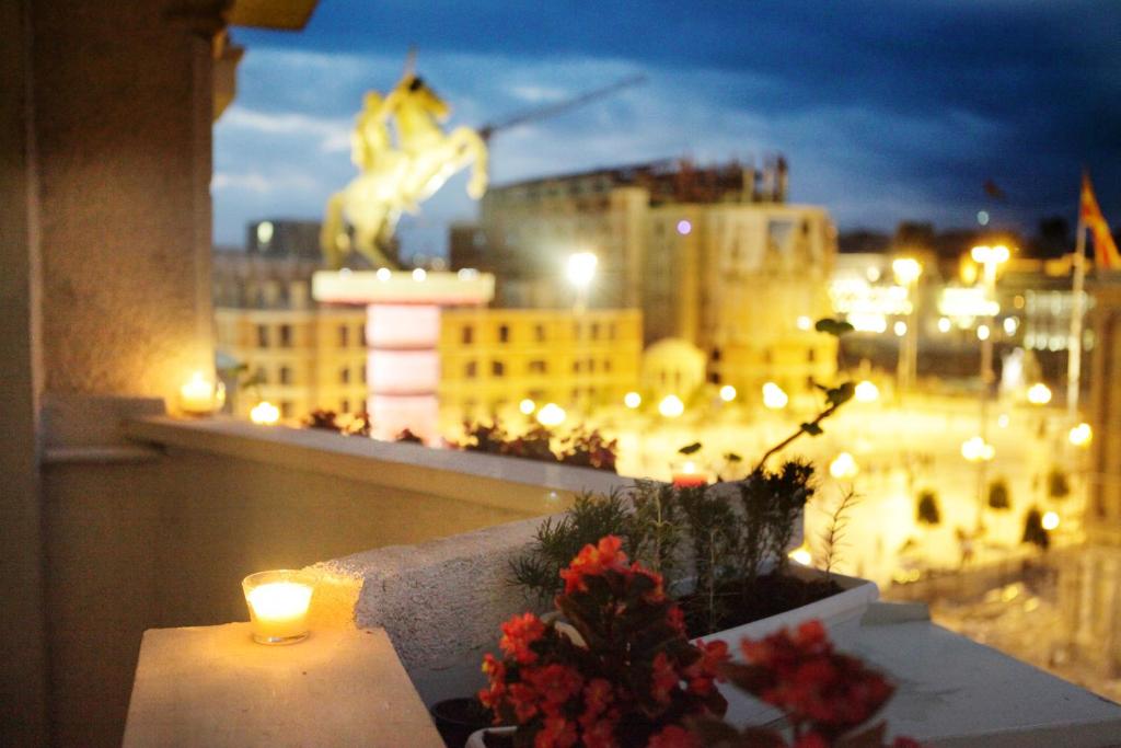 a candle on a balcony with a view of a city at Skopje City Square View in Skopje