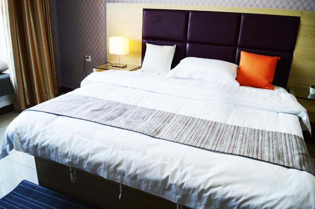 شقة قيشيتسينغيا مجمع فندق بازو في قوانغتشو: سرير كبير في غرفة الفندق مع وسائد برتقالية