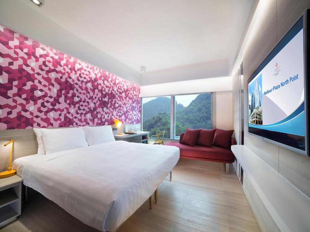 a hotel room with a large bed and a tv at Harbour Plaza North Point in Hong Kong