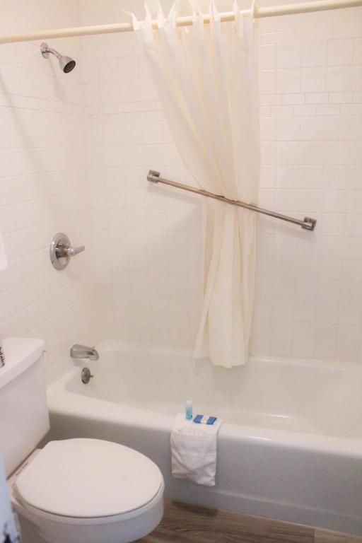 a bathroom with a white toilet and a tub and a sink at Chaparral Motor Inn in Burlington
