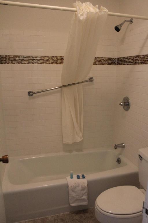 a bathroom with a white tub and a toilet at Chaparral Motor Inn in Burlington