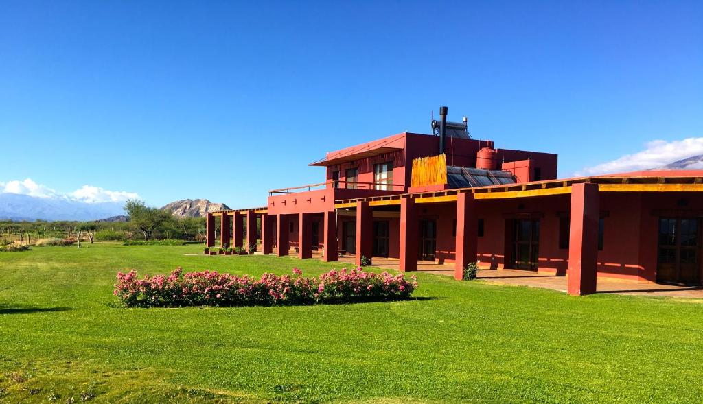 un bâtiment rouge avec des fleurs dans un champ dans l'établissement Finca Albarossa, à Fuerte Quemado