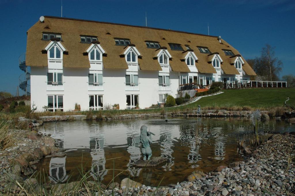 a building with a statue in a pond in front of it at Alago Hotel am See in Cambs