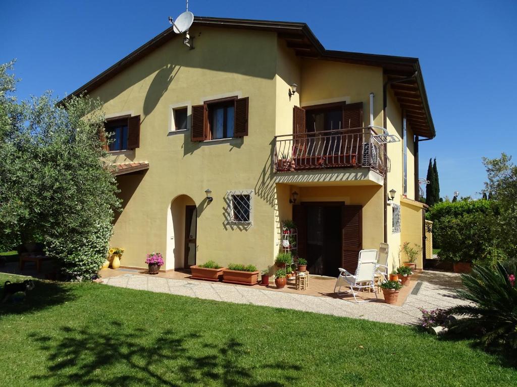 ein großes gelbes Haus mit Balkon und Hof in der Unterkunft B&B La Dolce Vita in Marsiliana