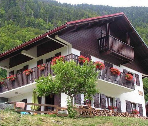 a house with balconies and a tree in front of it at L'Ancolie in Le Reposoir