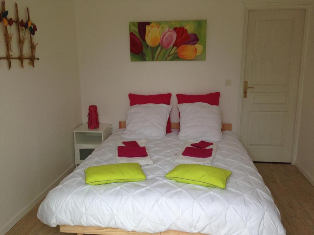 a bedroom with a white bed with two green pillows at Le Clos Saint Jean in Sainte-Honorine-des-Pertes