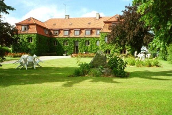 a large house with a white horse in a yard at Pension Elmehøj in Hjertebjerg