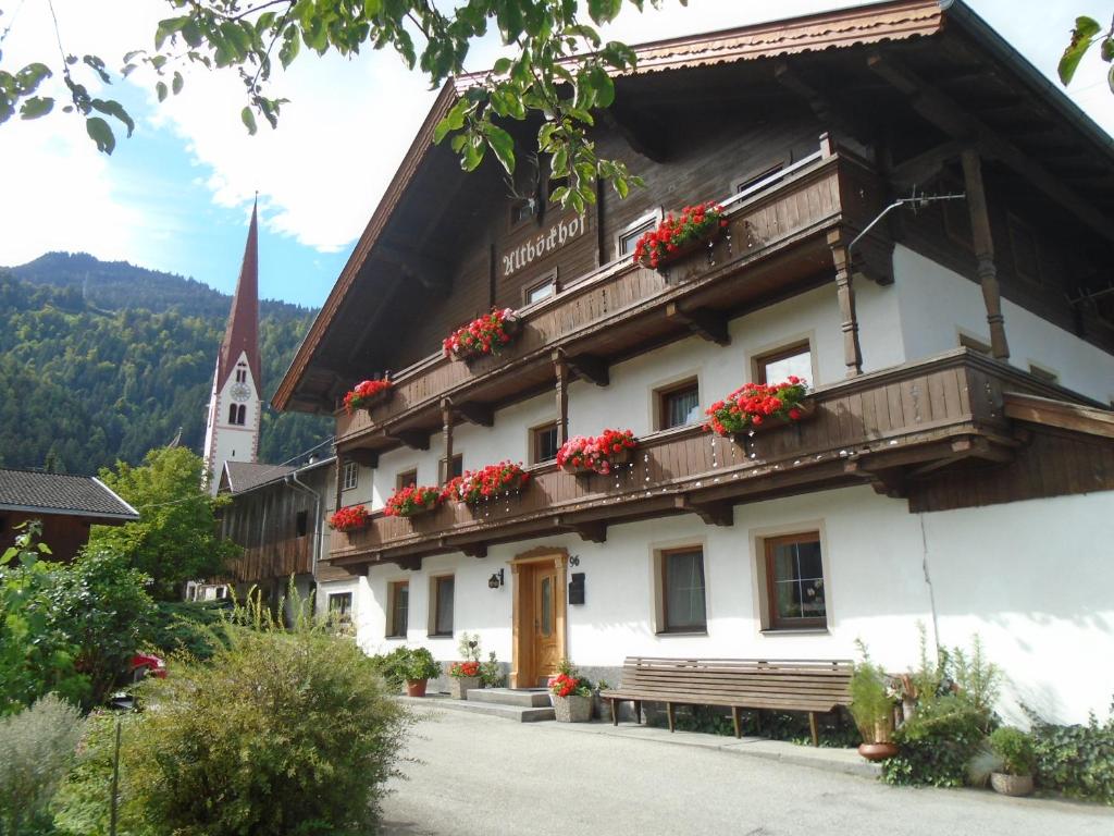 a building with flowers on the balconies and a church at Altböckhof in Schlitters