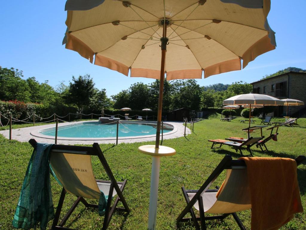 an umbrella and two chairs and a pool at Belvilla by OYO Rosa Gialla in Apecchio
