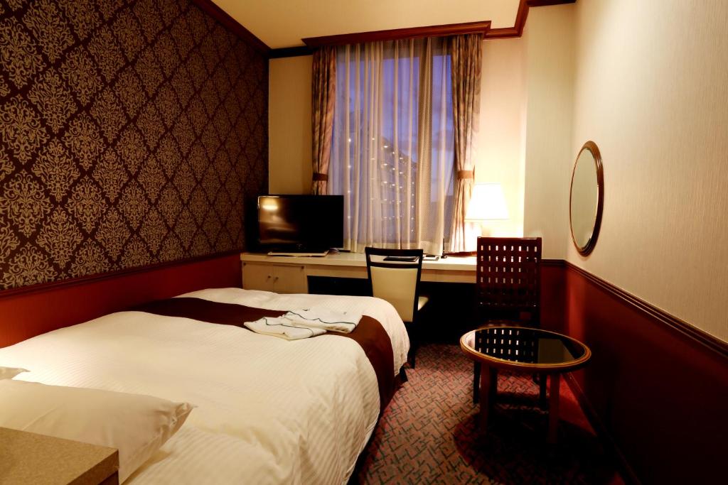 a hotel room with two beds and a desk at Hotel Sunlife Garden in Hiratsuka