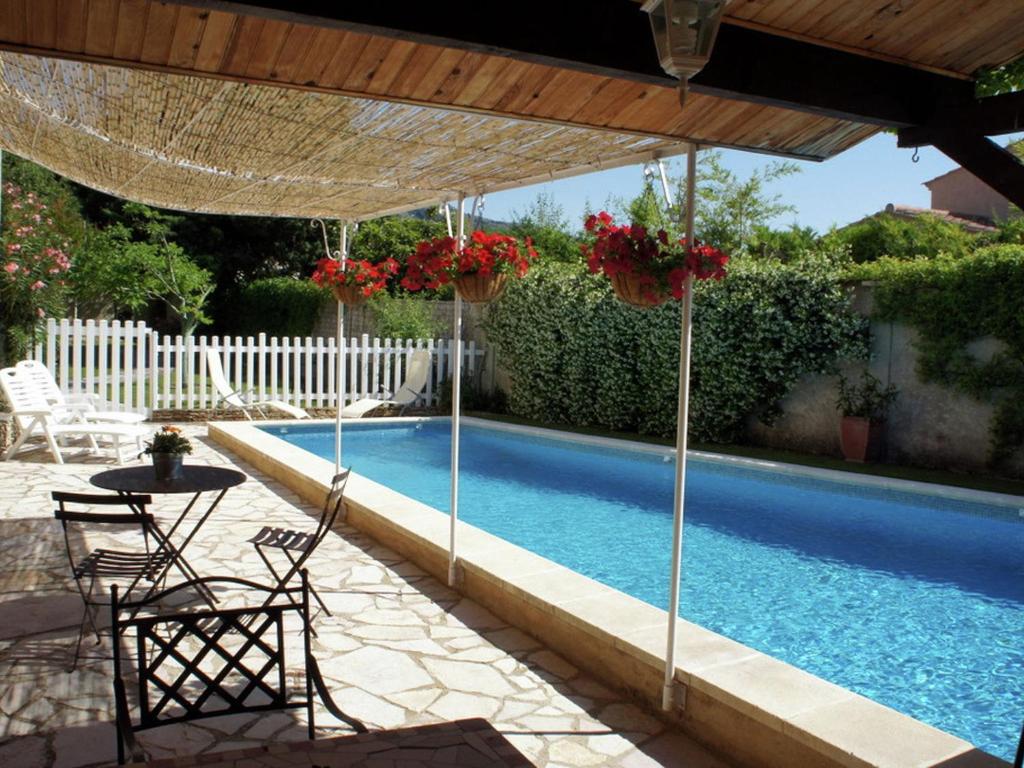 a swimming pool with a table and chairs under a umbrella at Charming holiday cottage with large private pool in Robion en Luberon