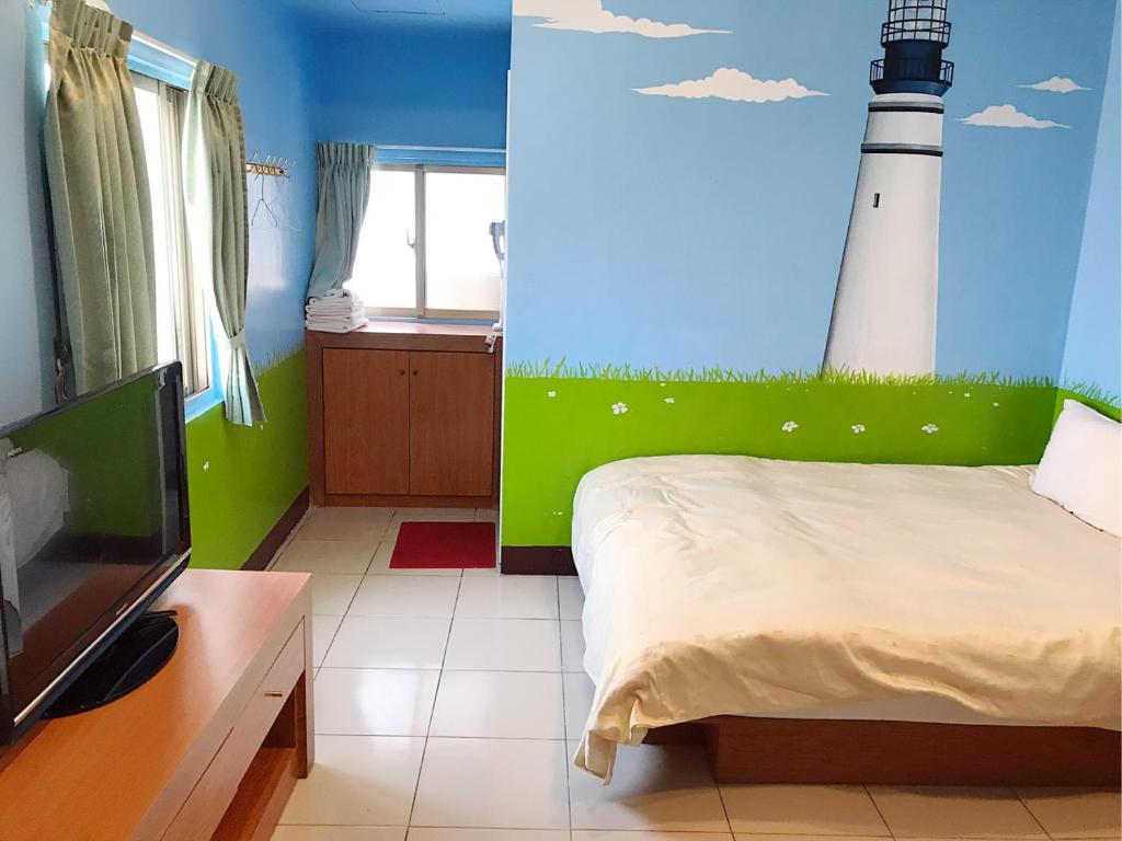 馬公市的住宿－海之島民宿 ，一间卧室配有一张床,墙上绘有灯塔。