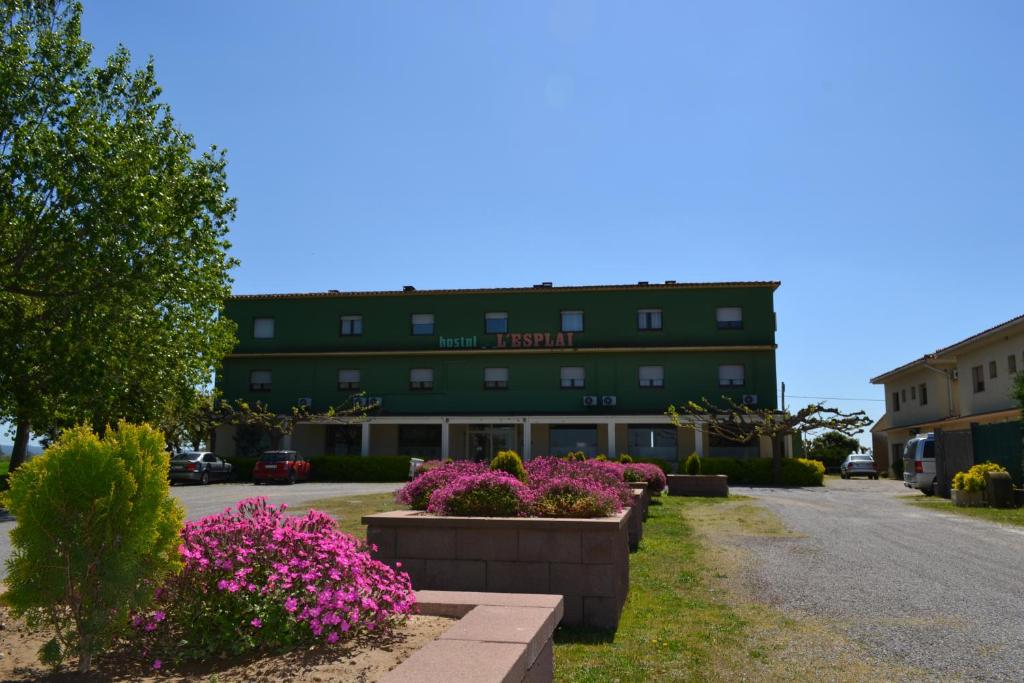 a green building with flowers in front of it at Hostal l'Esplai in Viladamat