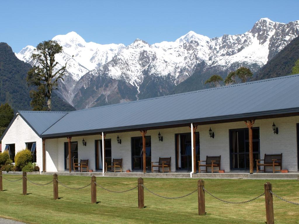 a white building with snow covered mountains in the background at Mt Cook View Motel in Fox Glacier