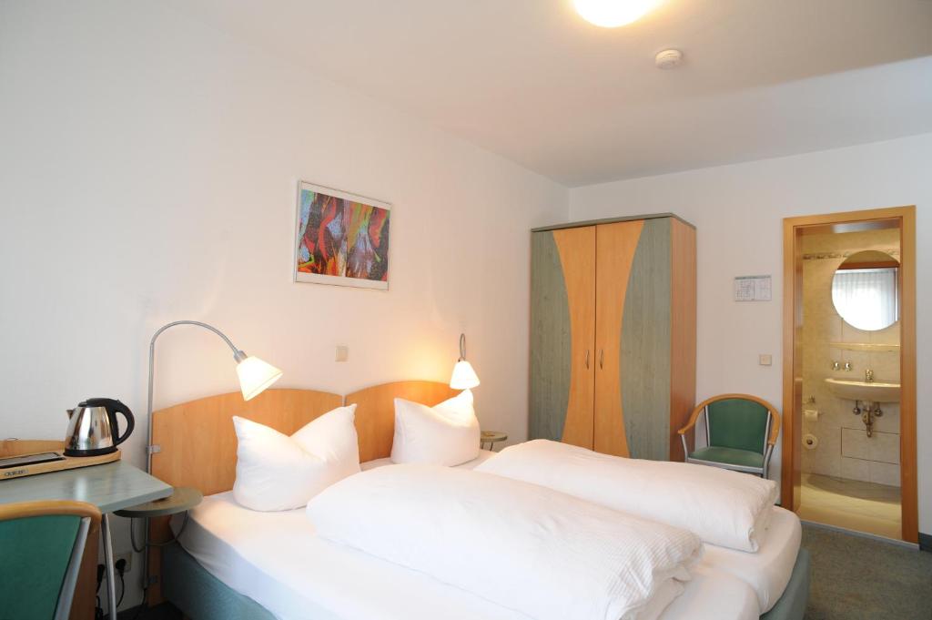 a bedroom with two white beds and a desk and a sink at Central-Classic Hotel in Stuttgart