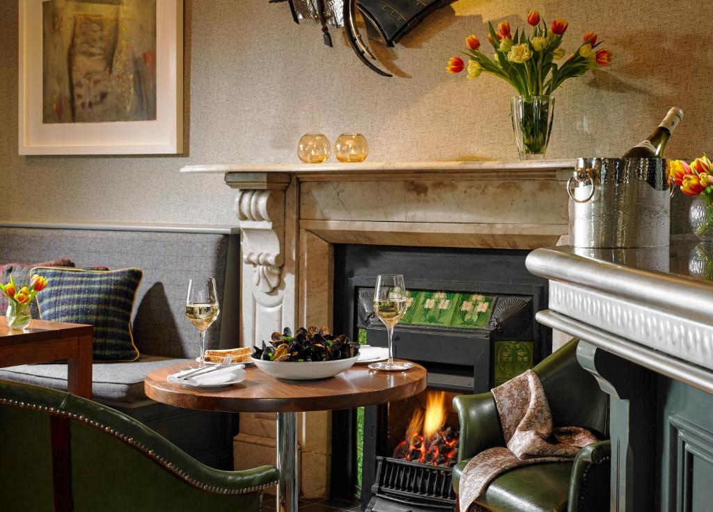 a living room with a fireplace and a table with wine glasses at Dunmore House Hotel in Clonakilty