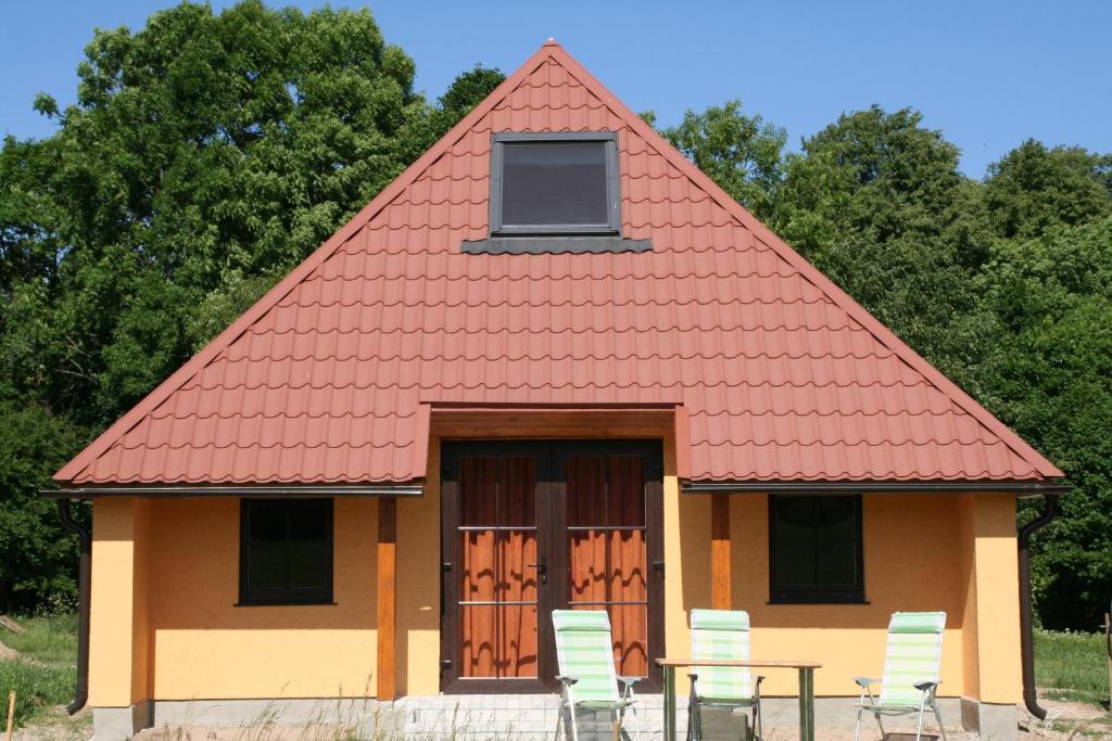 una pequeña casa con techo rojo y sillas en Fox House, en Pelči