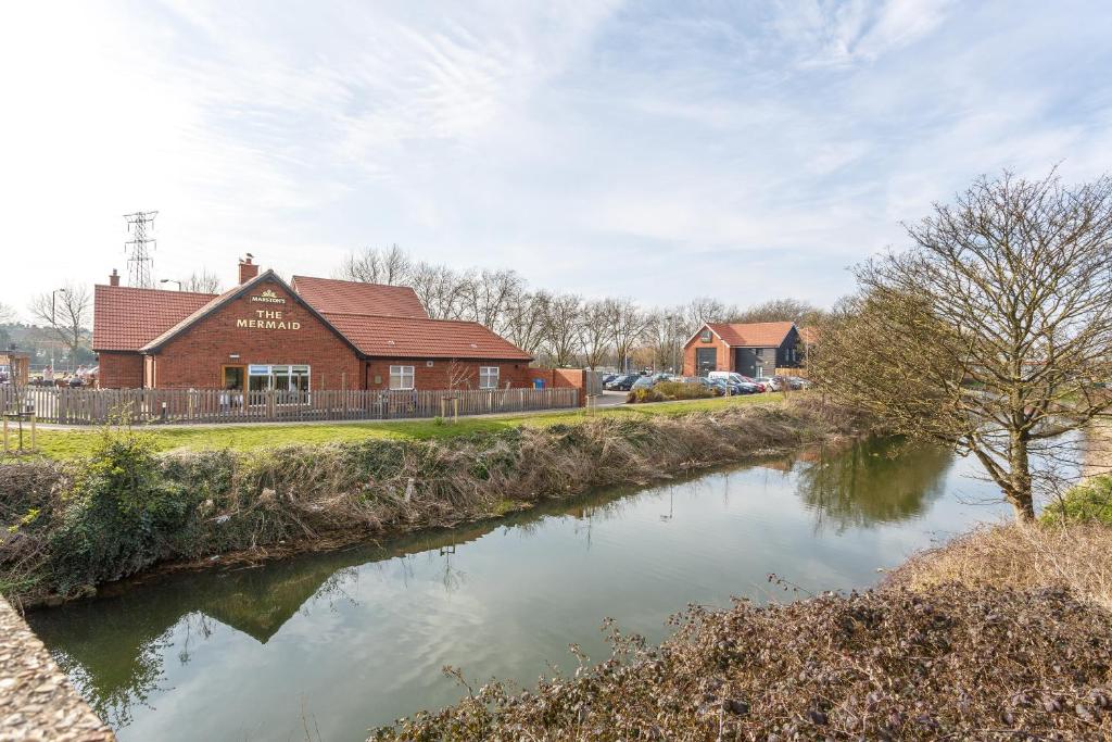 a building next to a river next to a building at Mermaid, Ipswich by Marston's Inns in Ipswich