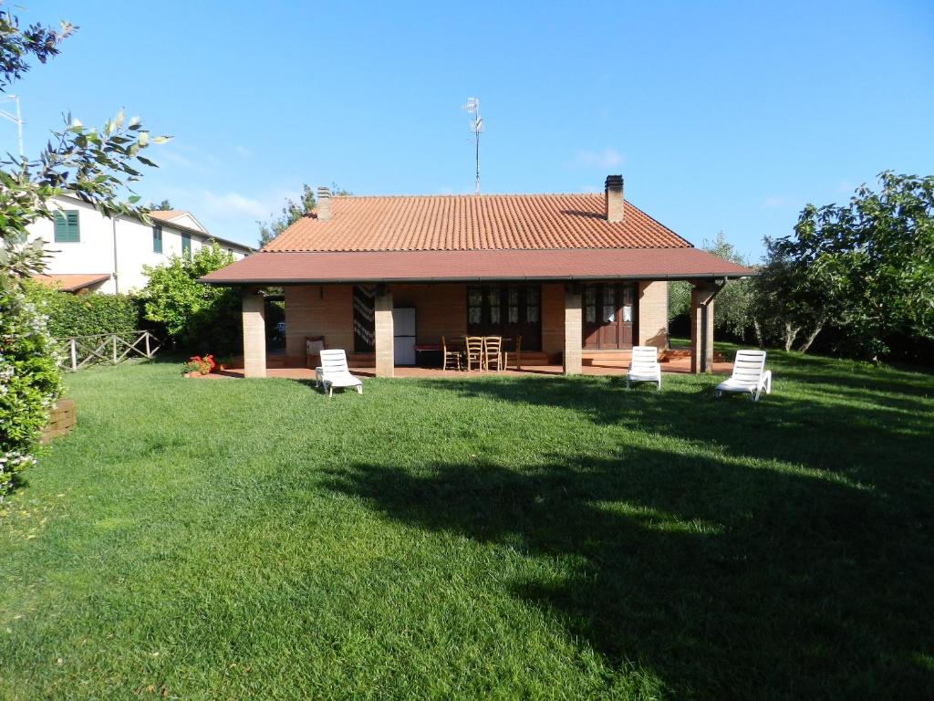 uma casa com um quintal com duas cadeiras brancas em Agriturismo Casa Guidoni em Follonica