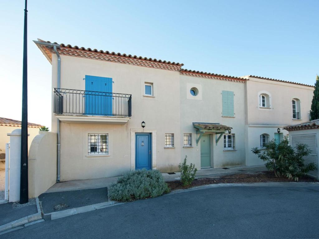 a white house with blue doors and a driveway at Modern villa near the sea with balcony in Aigues-Mortes