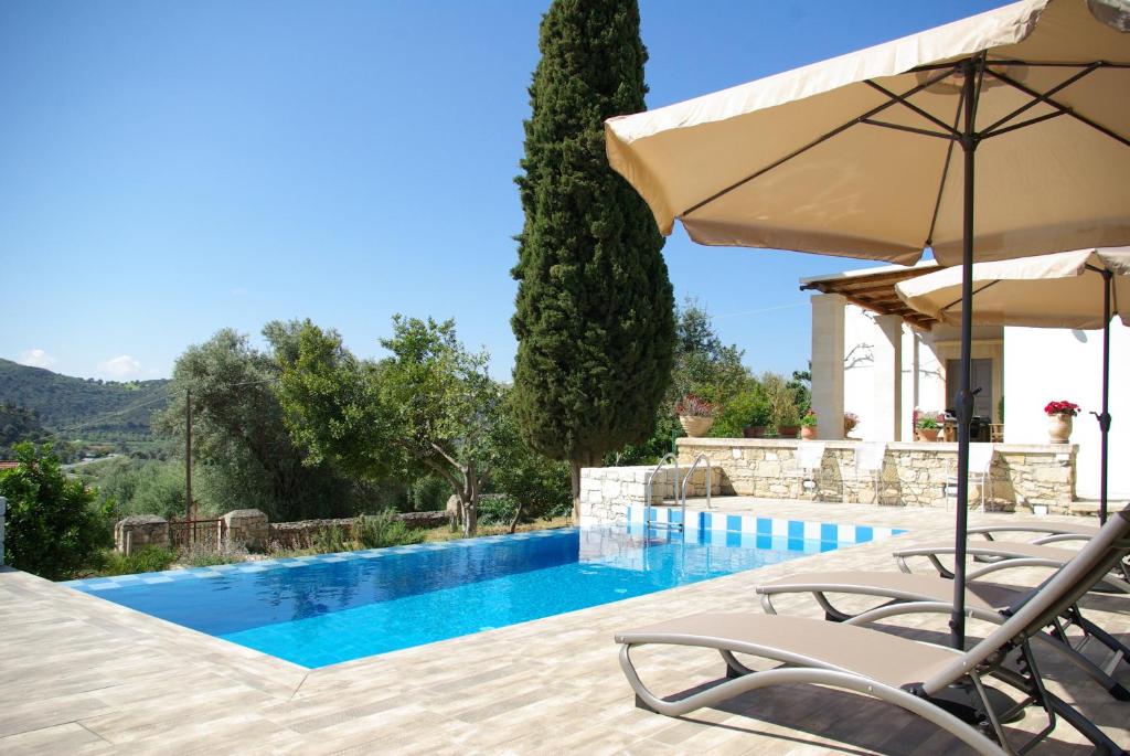 Vóroi的住宿－Villa Vigles，一个带两把椅子和遮阳伞的游泳池