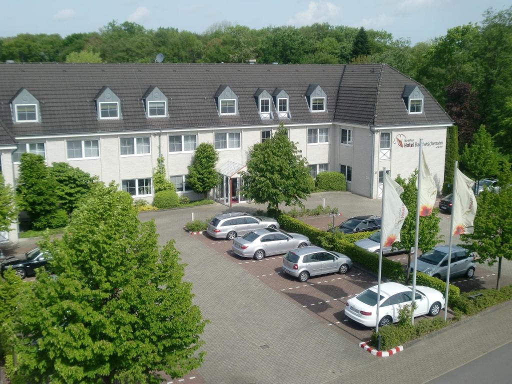 ein Apartmenthaus mit Autos auf einem Parkplatz in der Unterkunft NordWest-Hotel Bad Zwischenahn in Bad Zwischenahn