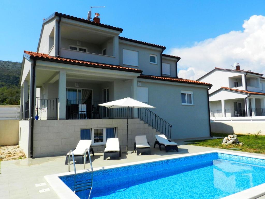 a house with a swimming pool in front of a house at VILLA AMBER YourCroatiaHoliday in Drenje