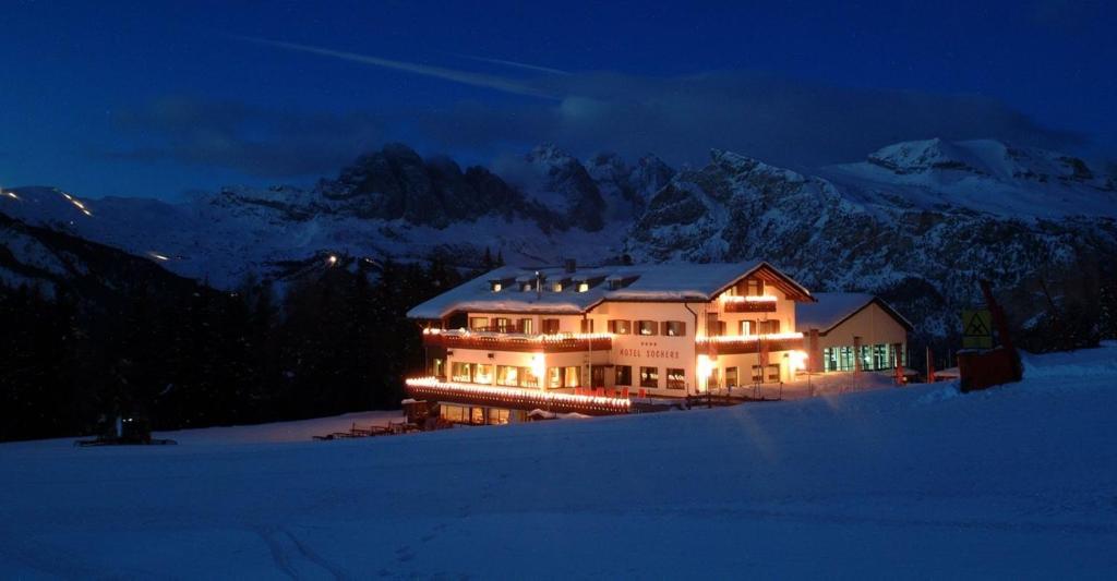 a large house in the snow at night at Hotel Sochers Club in Selva di Val Gardena