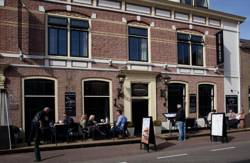 een groep mensen die aan tafels buiten een gebouw zitten bij Studio's de Domburger in Domburg