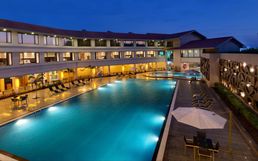 una piscina de hotel con mesas y sillas por la noche en Iscon The Fern Resort & Spa, Bhavnagar en Bhavnagar