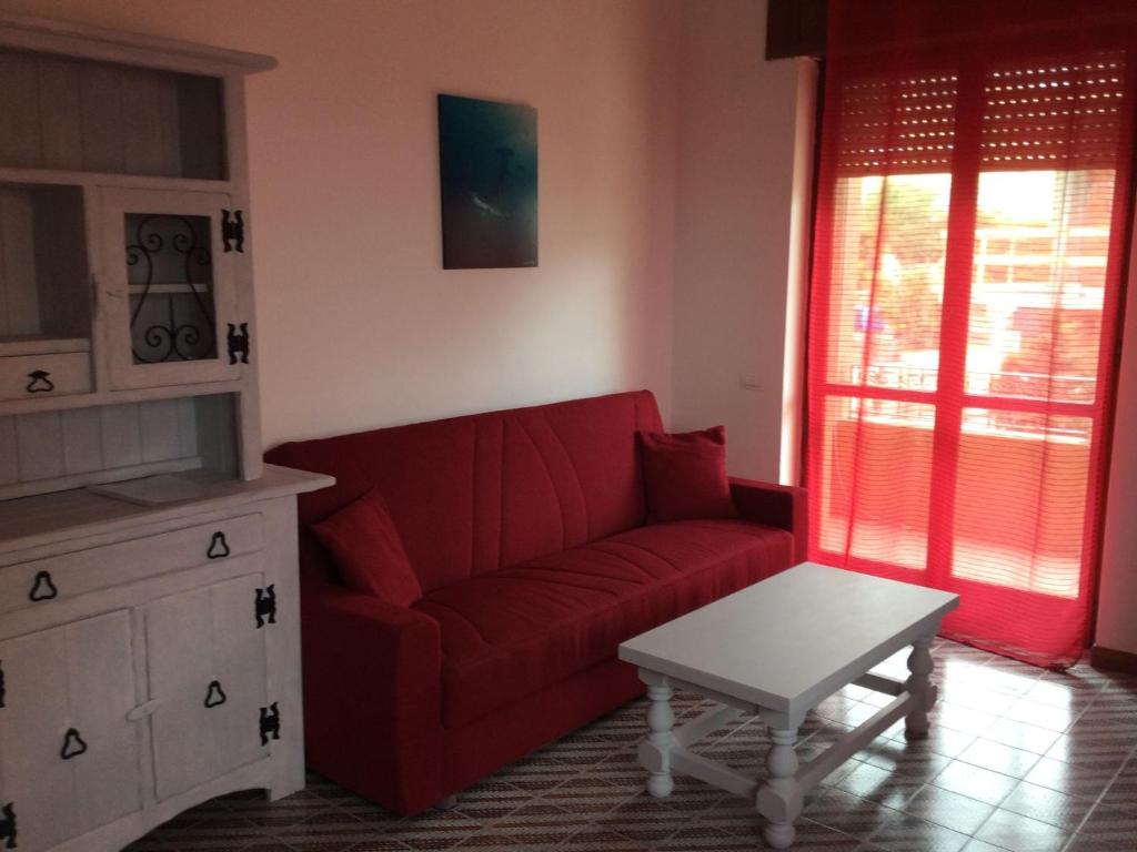 un soggiorno con divano rosso e tavolo di Modern Apartment in Sardinia with shared Pool a Santa Teresa di Gallura