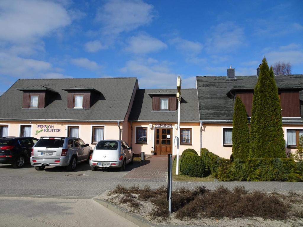 a house with cars parked in a parking lot at Pension Richter in Ueckeritz