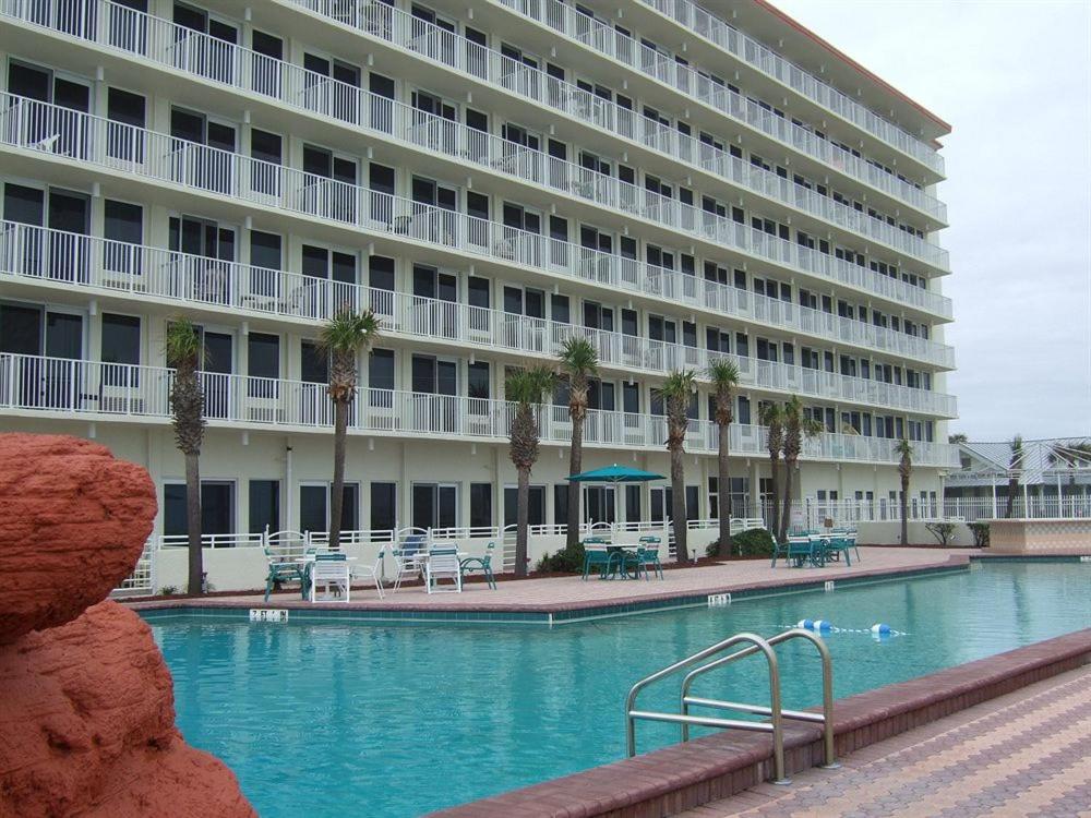 a hotel with a swimming pool in front of a building at Getaway That's Fit for a Queen in Daytona Beach