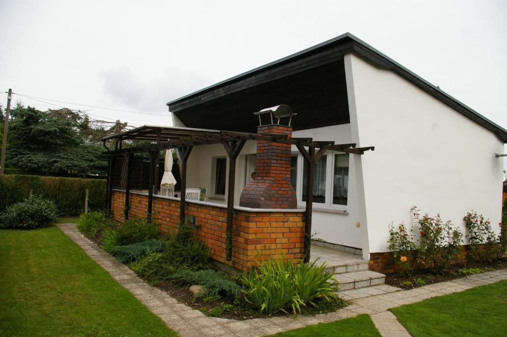 a white house with a black roof and a brick chimney at Ferienhaus Krüger in Loissin