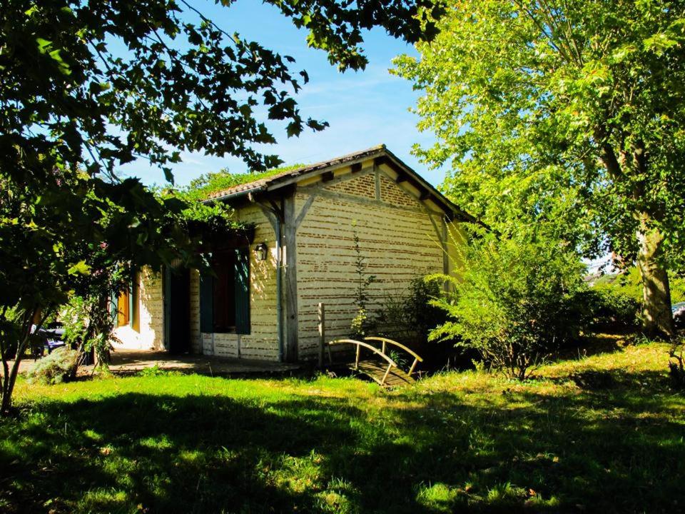 une vieille maison dans une cour avec de l'herbe et des arbres dans l'établissement Gites du Domaine Maison DoDo, à Lamonzie-Saint-Martin