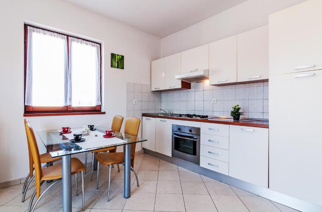 kuchnia z białymi szafkami, stołem i krzesłami w obiekcie Apartments Andrej w mieście Zadar