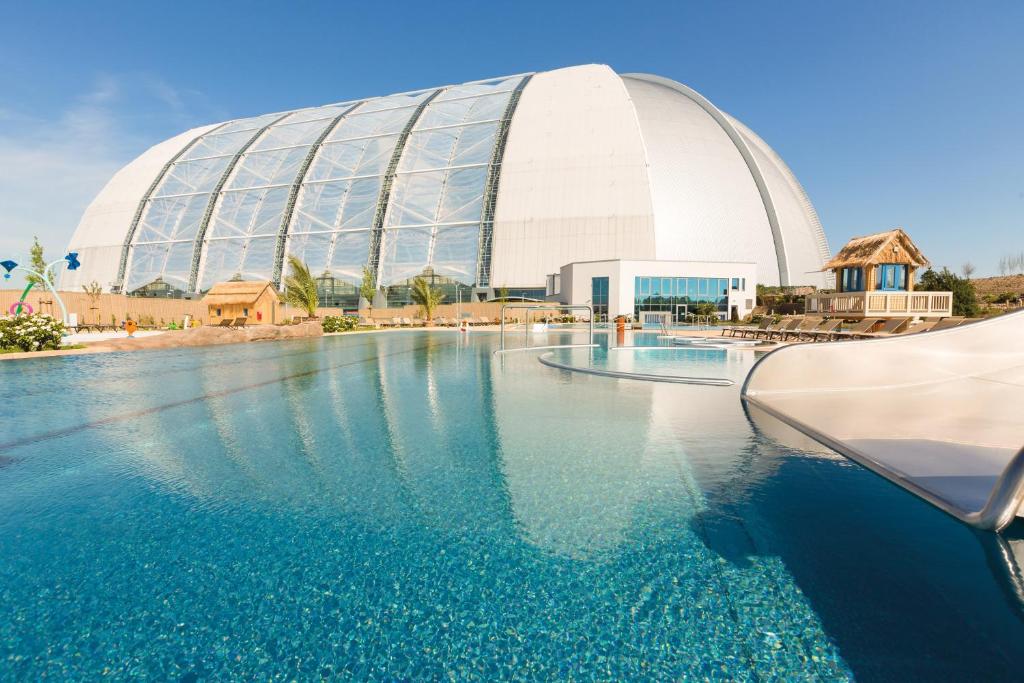 a swimming pool with a large building in the background at Tropical Islands in Krausnick
