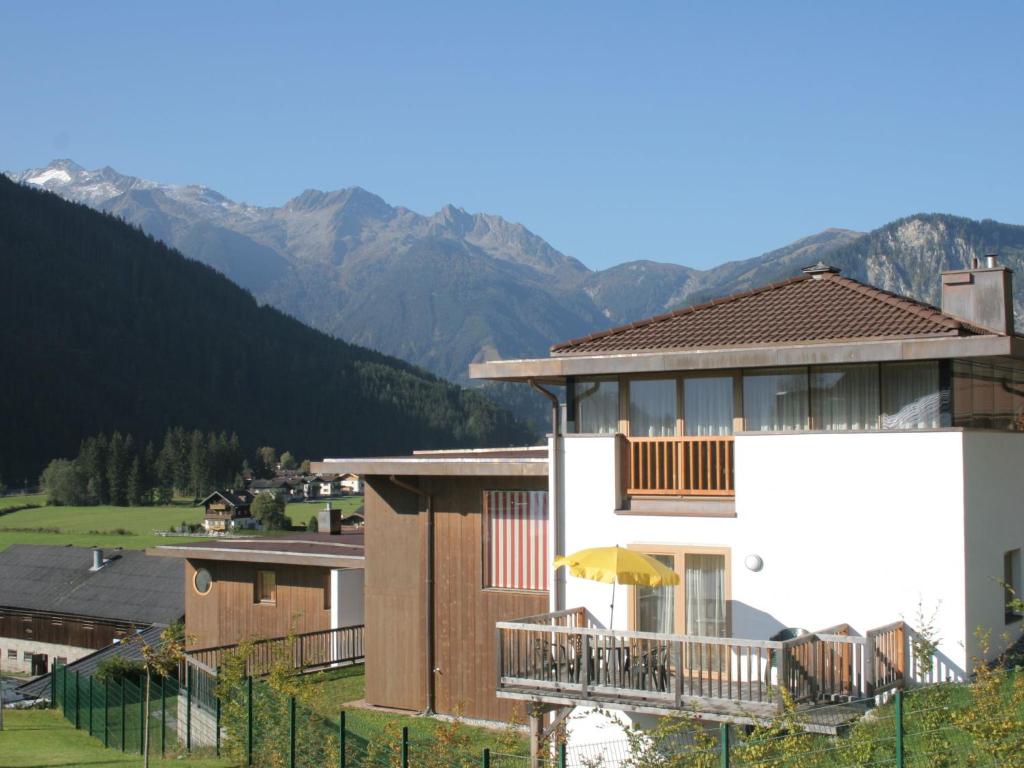 um edifício com varanda e montanhas ao fundo em Maisonette Am Bad em Wald im Pinzgau