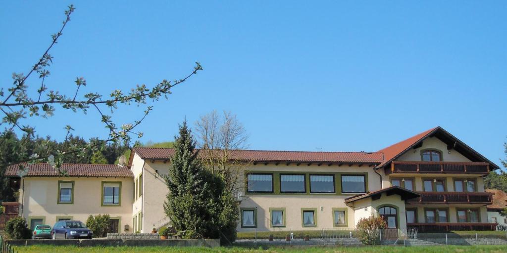 ein großes Haus mit rotem Dach in der Unterkunft Hotel Lugerhof in Weiding