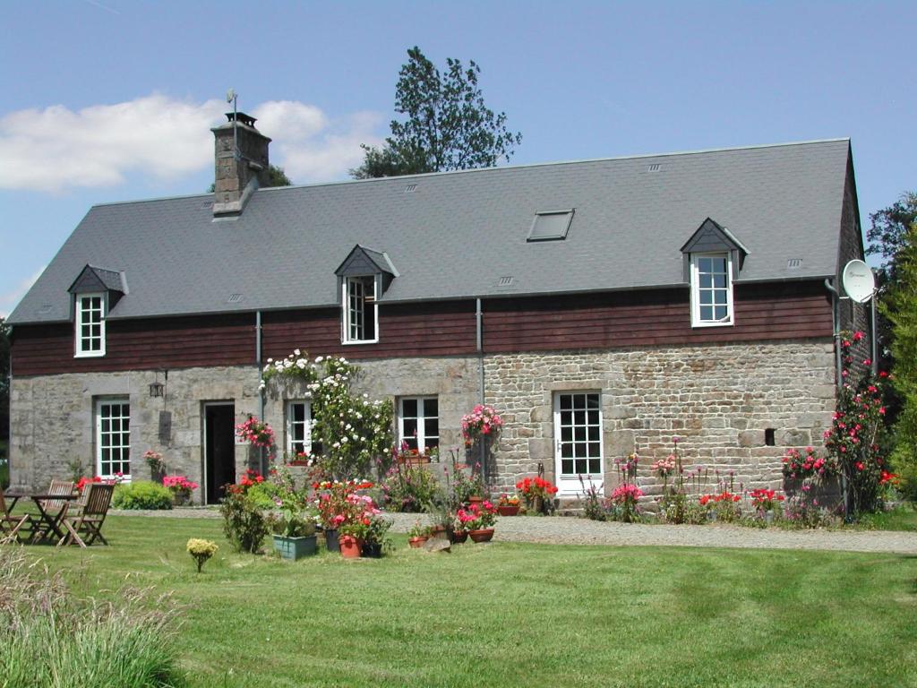 een stenen huis met bloemen ervoor bij L'Auvraire B&B in Coulouvray-Boisbenâtre