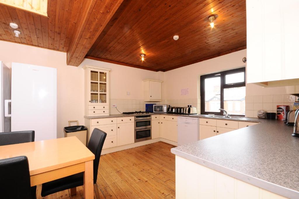 a kitchen with white cabinets and a wooden ceiling at The Rathmore in Cambridge