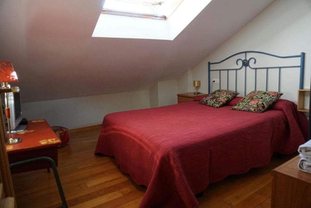 una camera da letto con un grande letto rosso e un lucernario di Casa Morrosco a Molinaseca