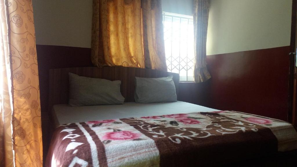 a bedroom with a bed with a floral blanket on it at Adinkra City Hotel in Kasoa