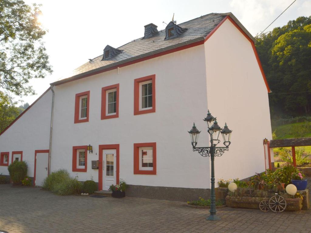 ein weißes Gebäude mit roten Fenstern und einem Straßenlicht in der Unterkunft Country house with private garden in Heidweiler