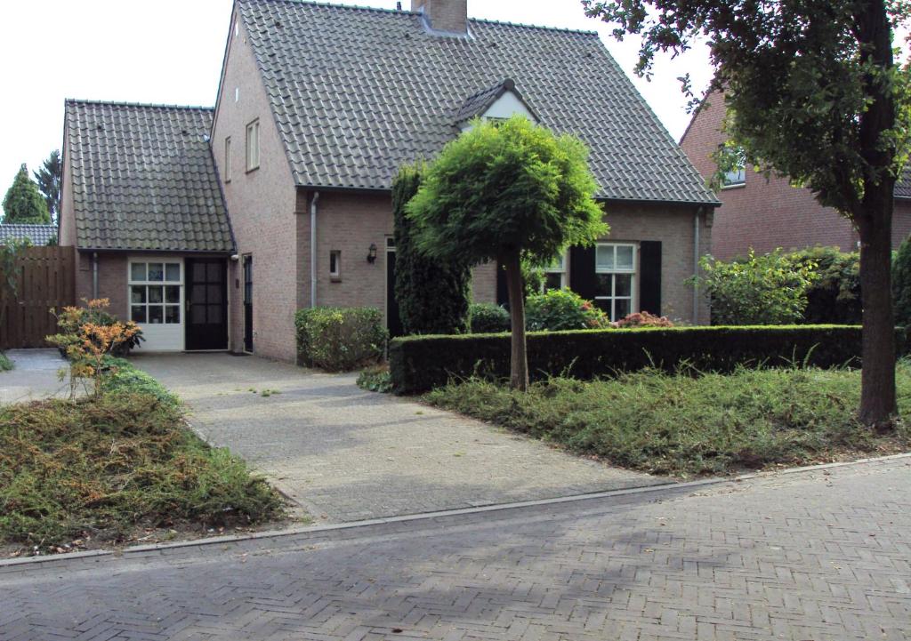 una casa con un árbol delante de una calle en B&B Eeneind en Nuenen