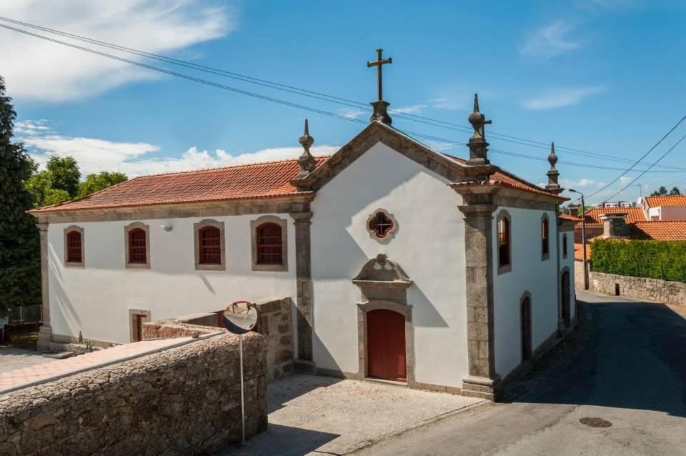 een kleine witte kerk met een rode deur bij Casa da Torre in Sobrosa