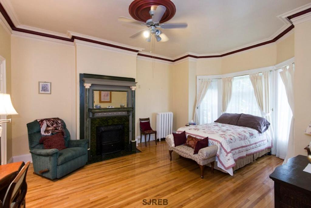 a bedroom with a bed and a chair and a fireplace at A Tanners Home Inn Bed and Breakfast in Saint John