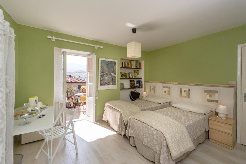 Bosio的住宿－Casa Bosio，一间卧室设有两张床、一张桌子和一个窗口。